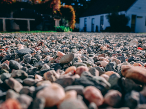 Dit is een foto van een pas aangelegde grindoprit. Op de achtergrond is een wit huis zichtbaar.