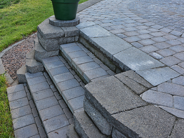Dit is een foto van trappen die van een grasveld naar een terras leiden.